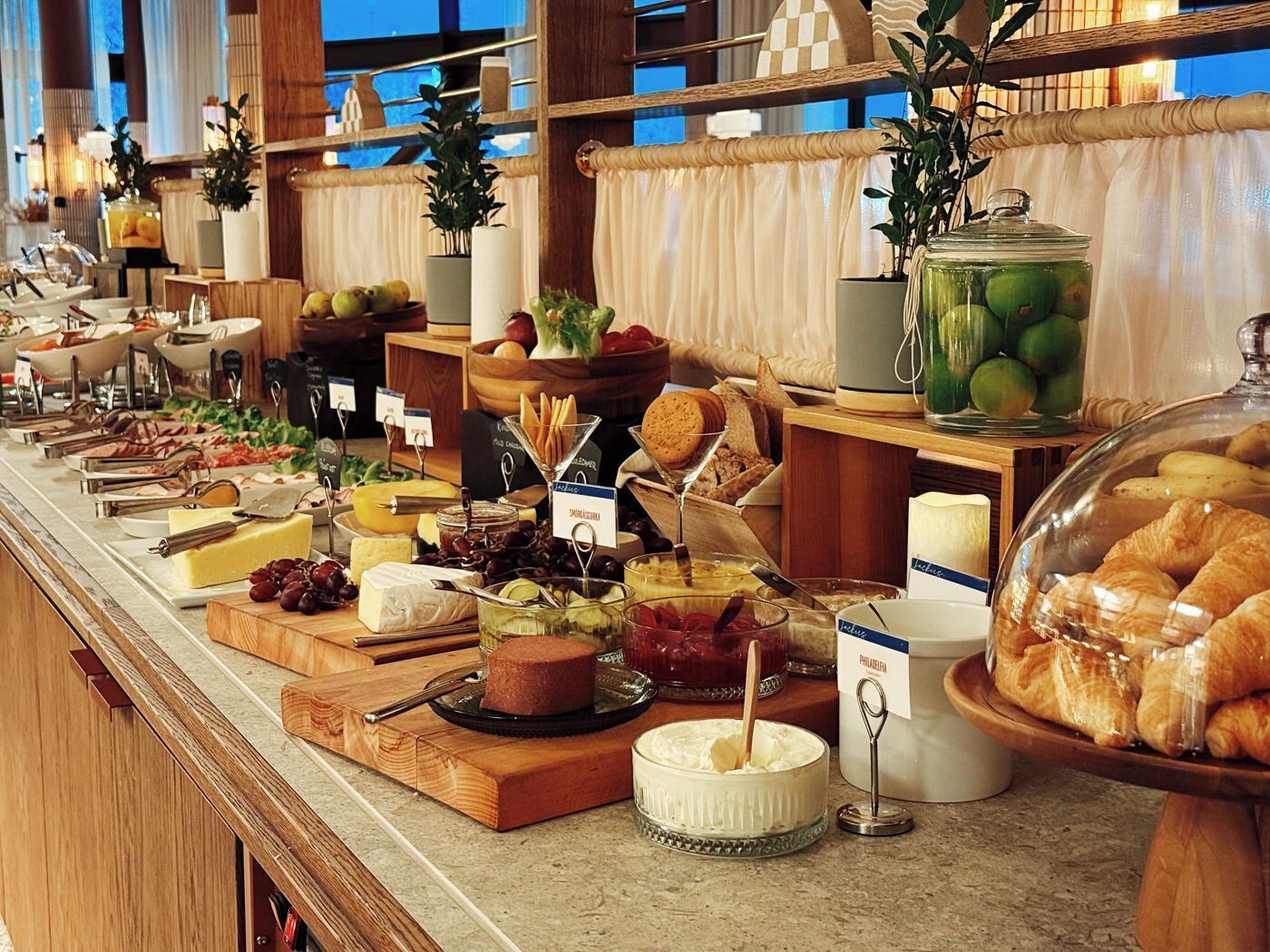 A buffet with various food items and a glass jar of green apples.