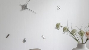 Un comedor moderno con una mesa de mármol, sillas grises y un reloj de pared minimalista.