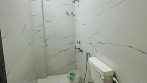 Une petite salle de bain blanche, équipée de toilettes, d’un bidet et d’une douche.