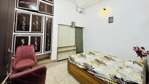 Une chambre à coucher avec un lit, une chaise rouge, un ventilateur de plafond et des décorations murales.