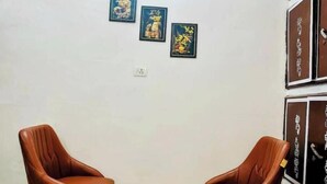 Une pièce comprenant deux fauteuils en cuir, une petite table et trois œuvres d’art encadrées accrochées au mur.