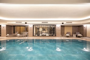 Una piscina amb gandules i un espai tancat de vidre amb equipament esportiu.