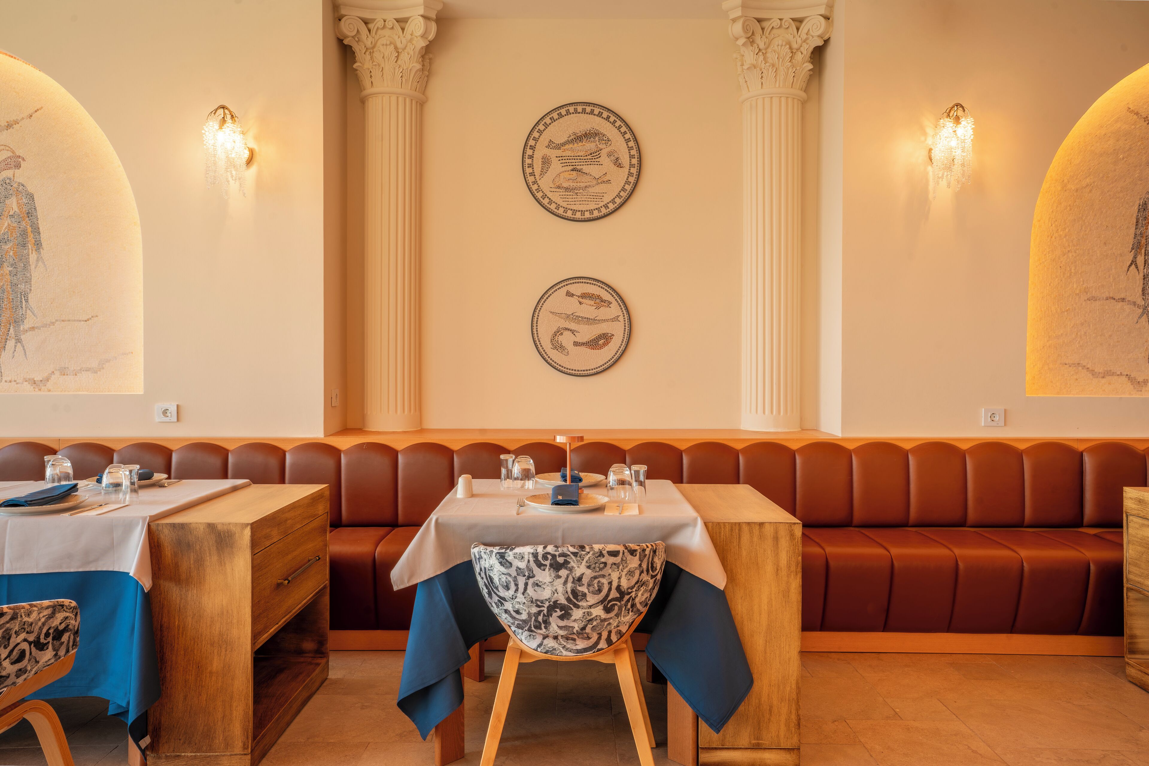 A restaurant with a wooden table, a patterned chair, and a brown booth.