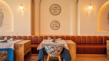 A restaurant with a wooden table, a patterned chair, and a brown booth.