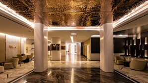 A spacious lobby with marble flooring, modern furniture, and a unique ceiling design. - Qlusive Hotel (Kusadasi)