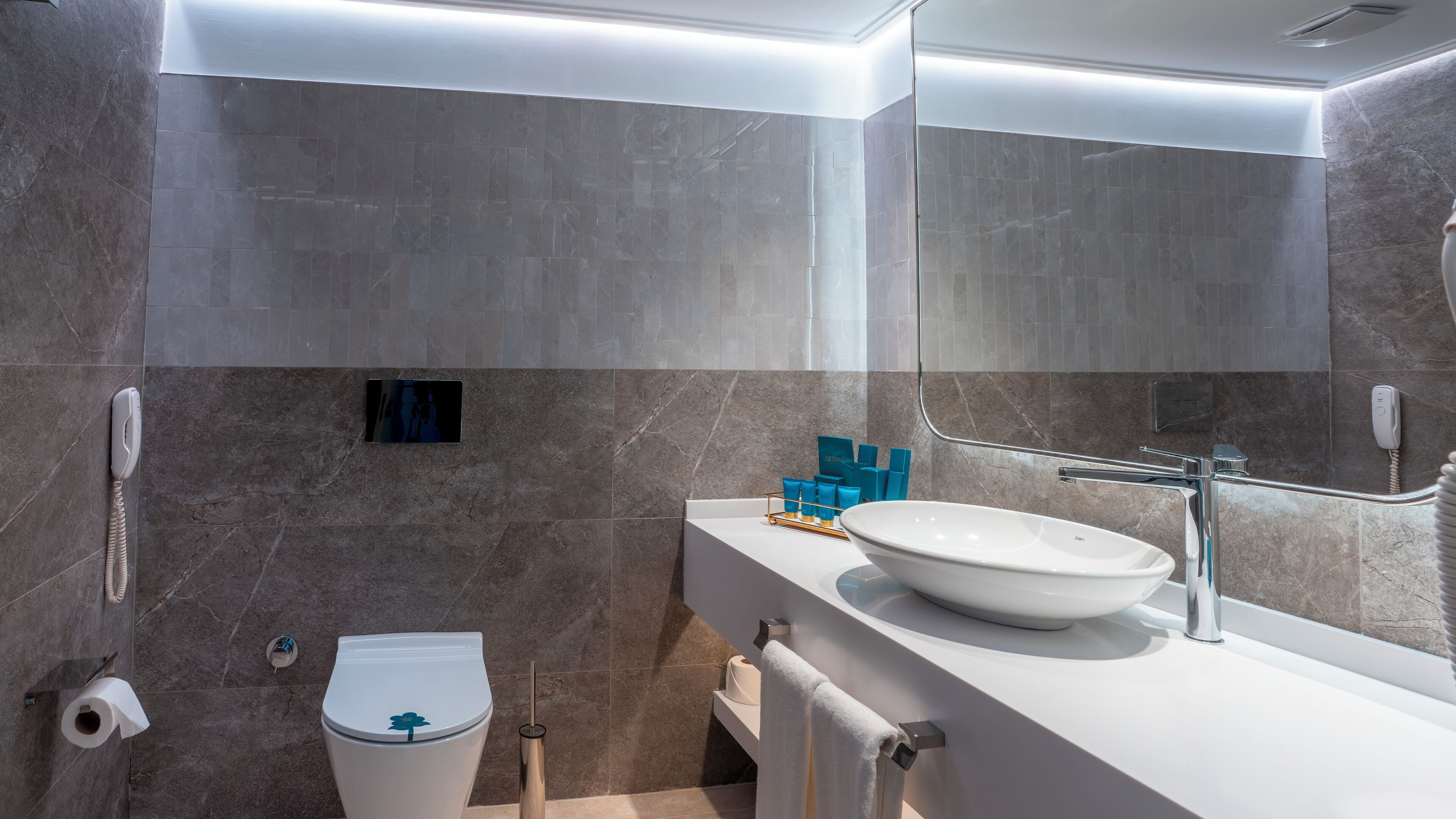 A modern bathroom with a white sink, a mirror, and a toilet.