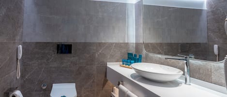 A modern bathroom with a white sink, a mirror, and a toilet.