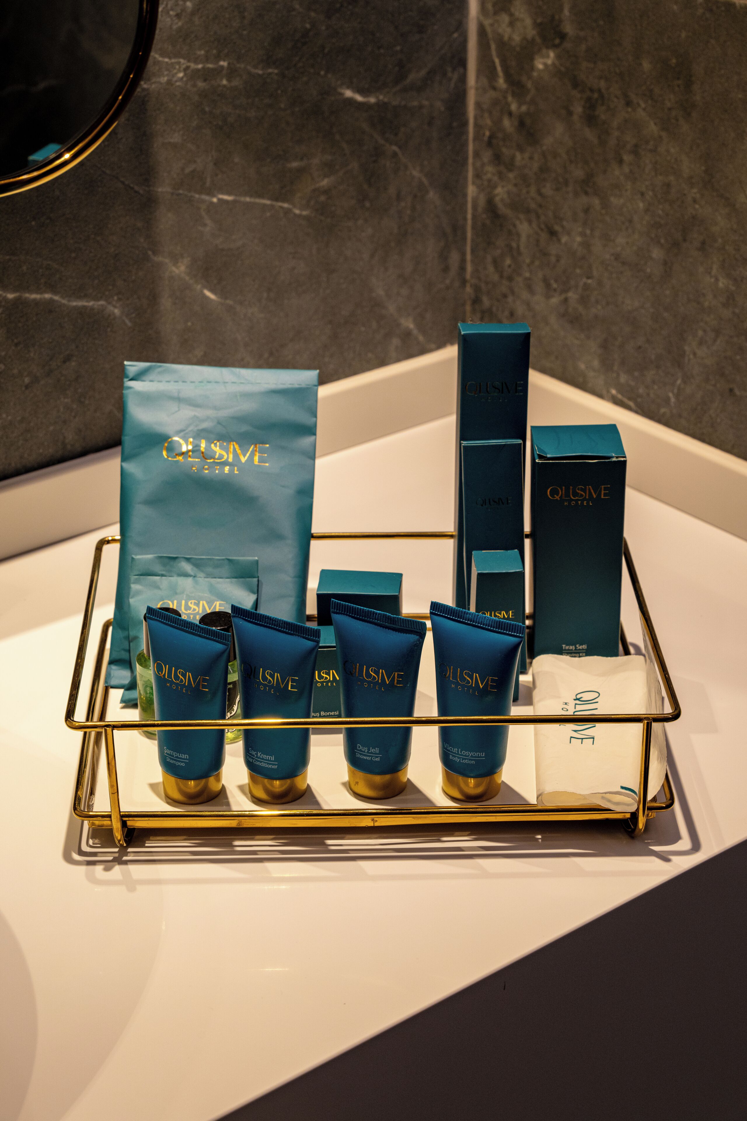 Un ripiano del bagno con articoli da toilette e una borsa QLUSIVE Hotel.