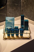 Un ripiano del bagno con articoli da toilette e una borsa QLUSIVE Hotel.