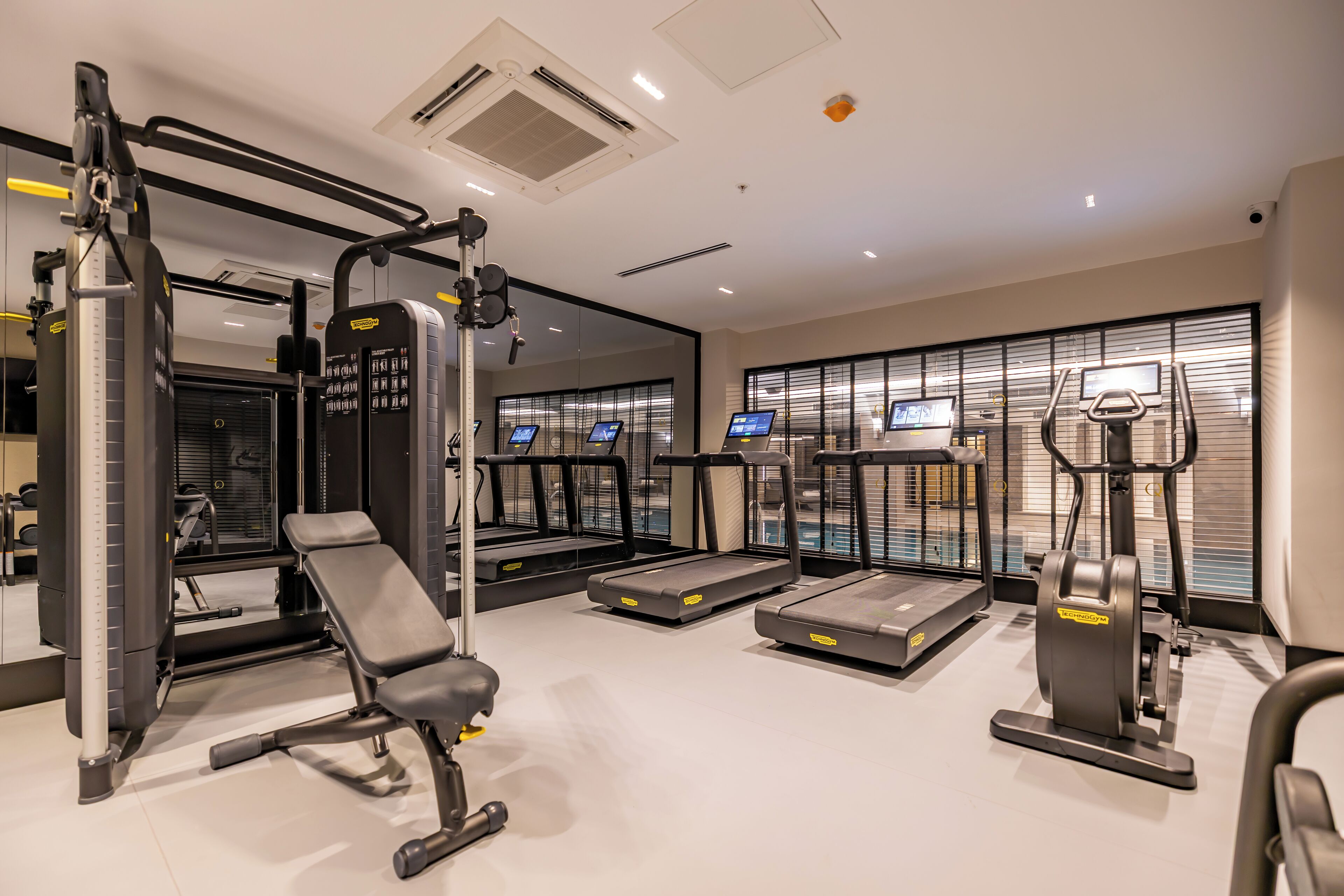 A modern gym with treadmills, a bench, and weight machines.