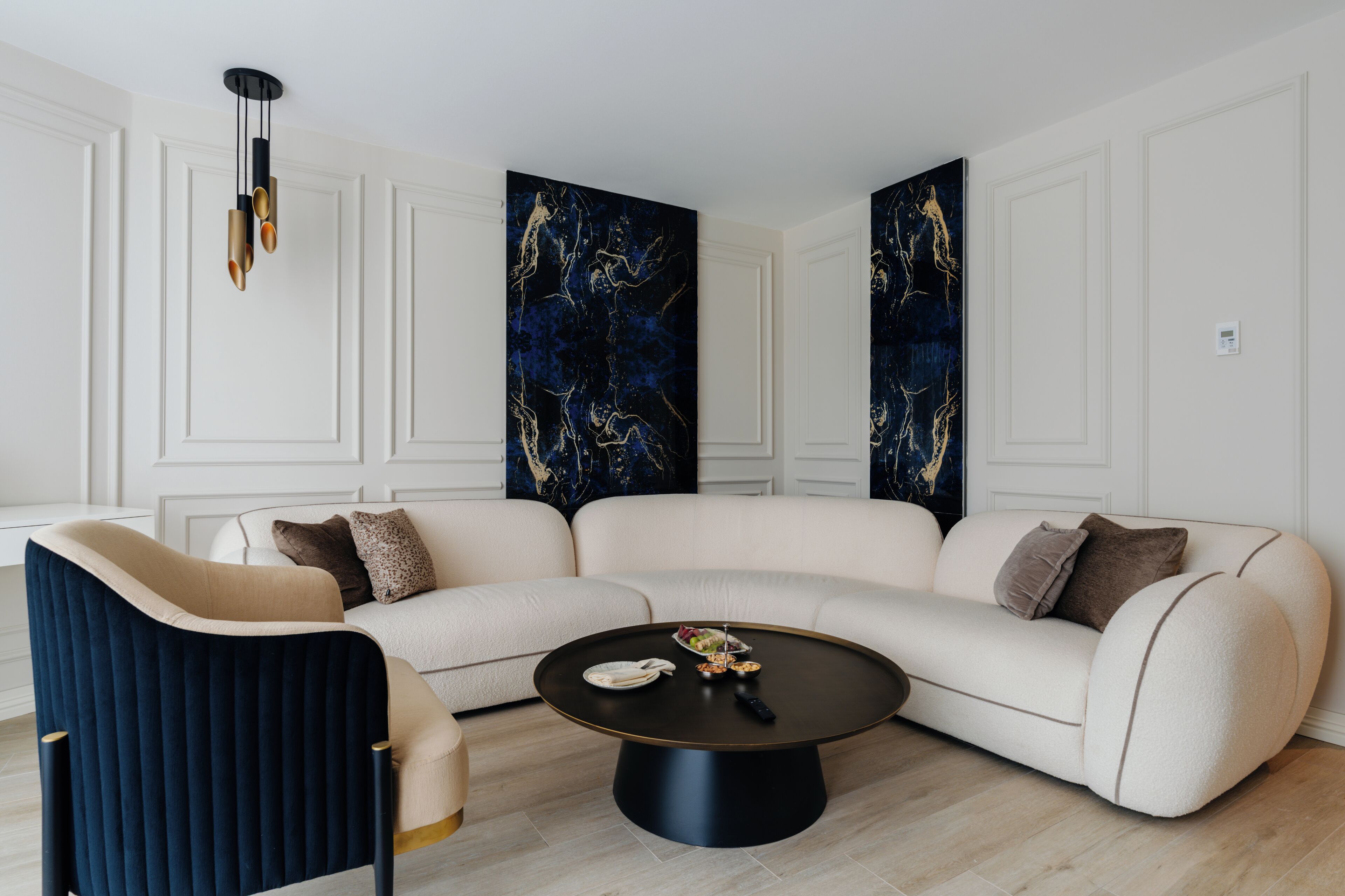 A modern living room with a sectional sofa, a round coffee table, and a hanging light fixture.