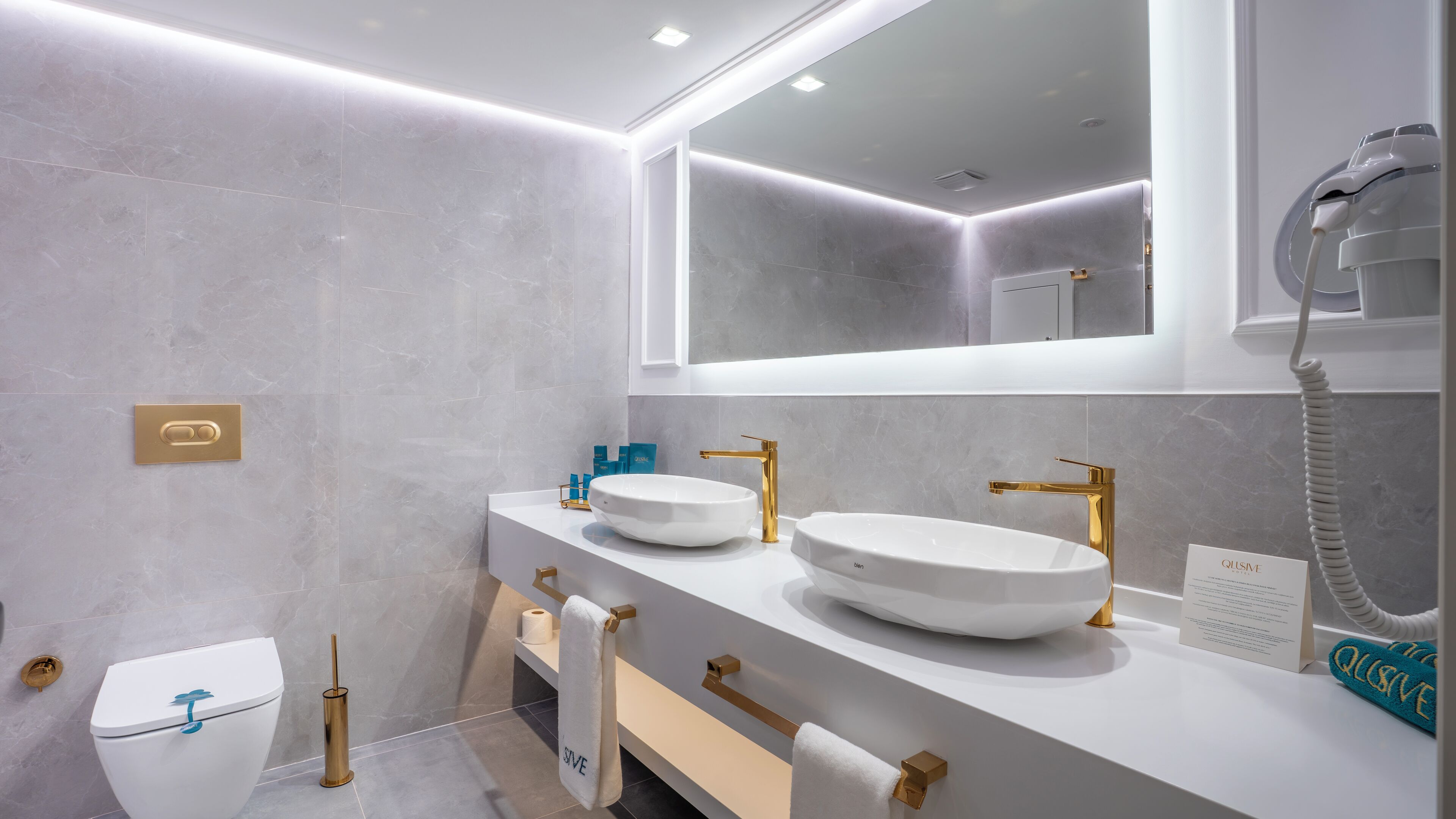 Une salle de bain moderne avec deux lavabos, des toilettes et un sèche-cheveux.