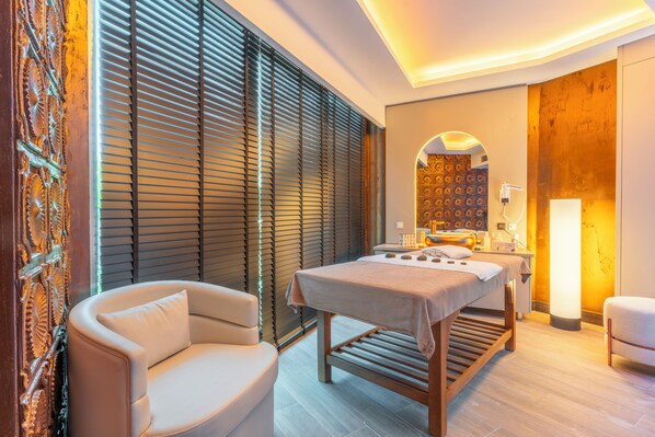 A spa room with a massage table, a cushioned chair, and a large mirror. - Qlusive Hotel (Kusadasi)