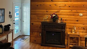 Ein gemütliches Wohnzimmer mit Kamin, Holzvertäfelung, einer Tür mit Glaseinsätzen und einem kleinen Tisch mit Dekoration.