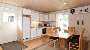 Een moderne keuken met witte kasten, een houten eettafel en een zwart tapijt.