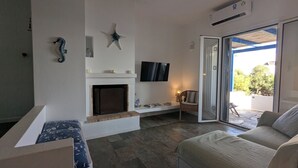 Un salon doté d’une cheminée, d’un téléviseur et d’une porte-fenêtre coulissante donnant sur un espace extérieur.