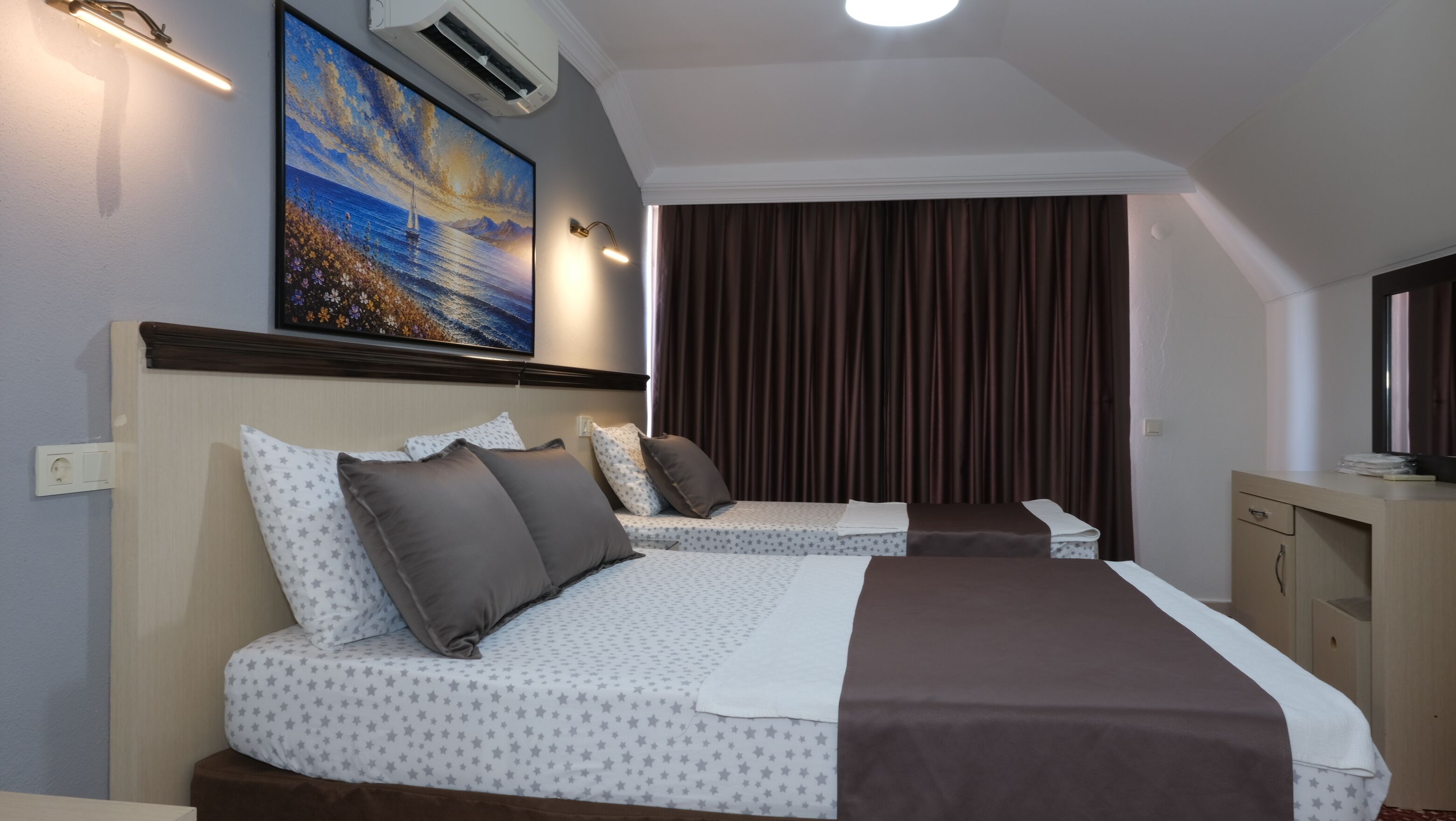 Habitación de hotel con dos camas, un cuadro, un equipo de aire acondicionado y un televisor.