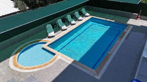 A rectangular swimming pool with a diving board, surrounded by lounge chairs and a small hot tub. - Azak Blue Otel (Alanya)