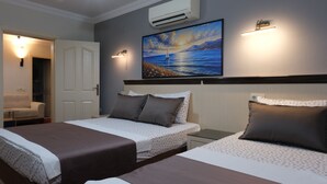Une chambre d’hôtel avec deux lits, un tableau représentant un paysage marin, un climatiseur et une lampe de chevet.