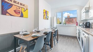 A modern kitchen with a window view, a dining area with a table set for four, and two artworks on the walls. - Lily House - 3 Bed WIFI & Parking Hull (Kingston upon Hull)