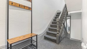A staircase with a wooden handrail and a bench at the bottom. - Lily House - 3 Bed WIFI & Parking Hull (Kingston upon Hull)