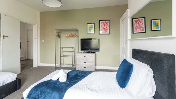 A bedroom with a bed, a TV, a wardrobe, and a mirror.