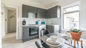 A modern kitchen with grey cabinets, a built-in oven, and a dining area with a table set for two.