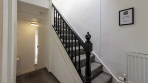 A staircase with a black handrail and a white wall with a framed sign.