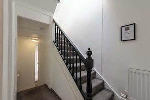 Eine Treppe mit schwarzer Handlauf und einer weißen Wand mit einem gerahmten Schild.