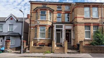 A two-story residential building with a corner entrance, a bay window on the first floor, and a brick facade.