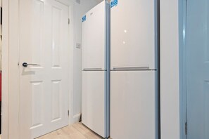 Un couloir avec des portes blanches et un réfrigérateur.