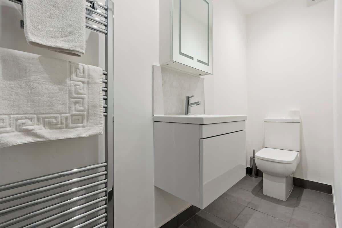 Une salle de bain moderne avec un lavabo blanc, des toilettes et un porte-serviettes orné de serviettes à motifs.