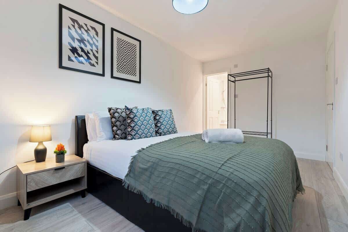 A modern bedroom with a bed, bedside table, lamp, and artwork on the wall.