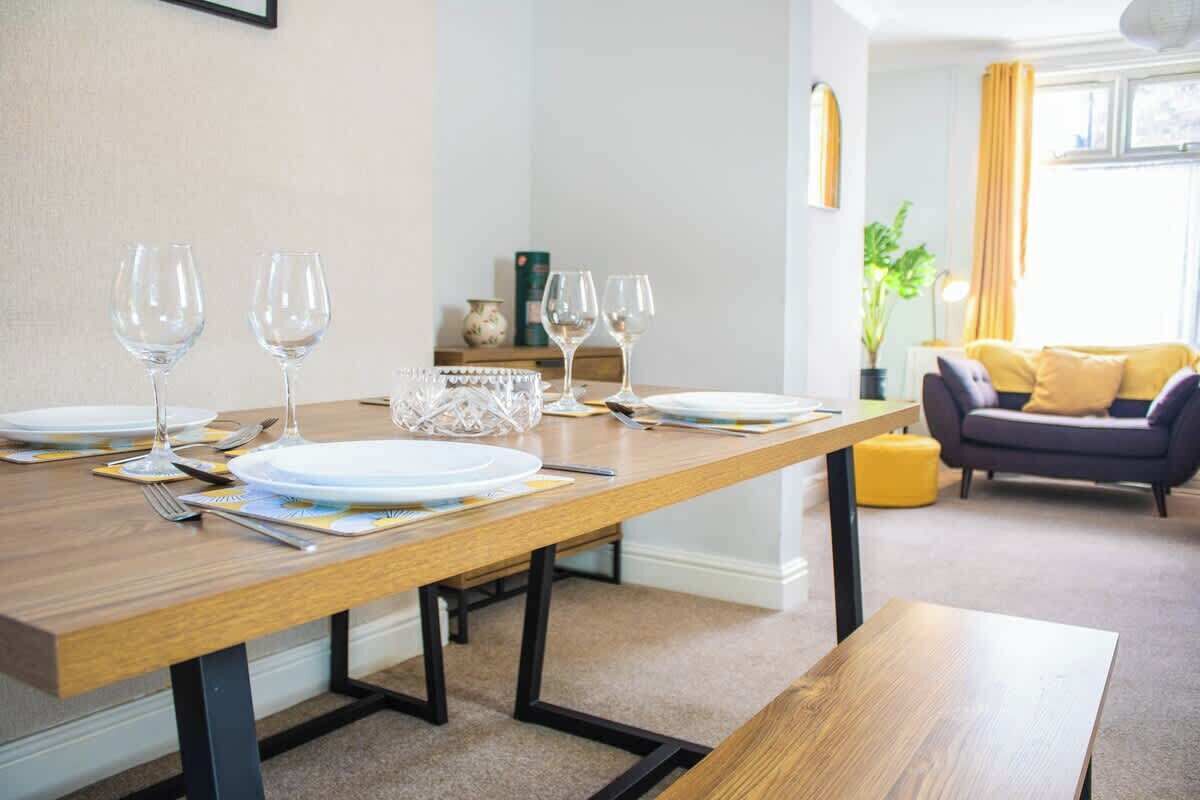A dining area with a wooden table set for four, including plates, glasses, and cutlery.