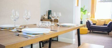 A dining area with a wooden table set for four, including plates, glasses, and cutlery.