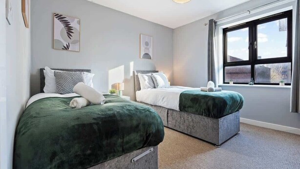 Habitación de hotel moderna con dos camas, un ventanal grande y vistas al exterior.