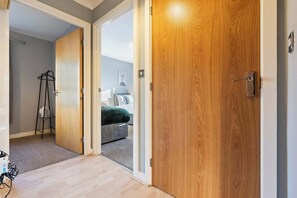 Un pasillo que conduce a un dormitorio con cama, mesita de noche y armario.
