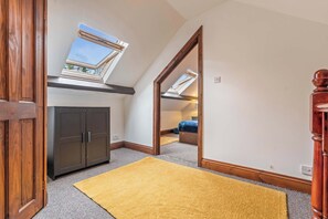 A room with a skylight, wooden wardrobe, and a yellow rug. - Daffodil Apartment 4 Bedroom in Pontypool (Torfaen Principal Area)