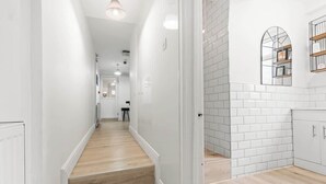 Una cocina moderna con azulejos blancos tipo metro, piso de madera y alacenas empotradas.