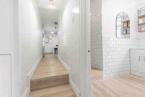 A modern kitchen with white subway tiles, wooden flooring, and built-in cabinetry.