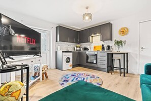Une cuisine moderne avec des meubles gris, un lave-linge et une machine à café.