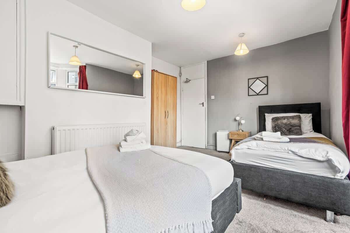 A bedroom with two beds, a large mirror, a bedside table, and a wardrobe.