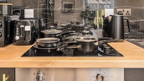 Een keuken met een zwart aanrecht, een fornuis, een koffiezetapparaat en een broodrooster.