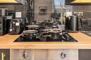 A kitchen with a black countertop, a stove, a coffee maker, and a toaster.