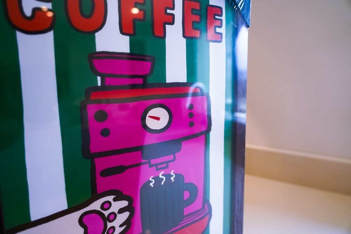 A colorful coffee-themed sign with a coffee machine illustration.