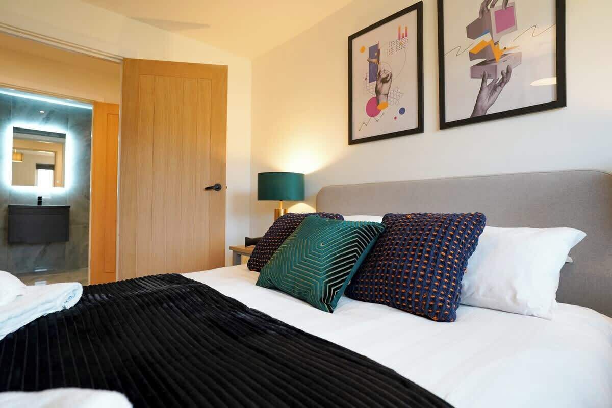 A hotel room with a bed, a nightstand, a lamp, and two framed artworks on the wall.