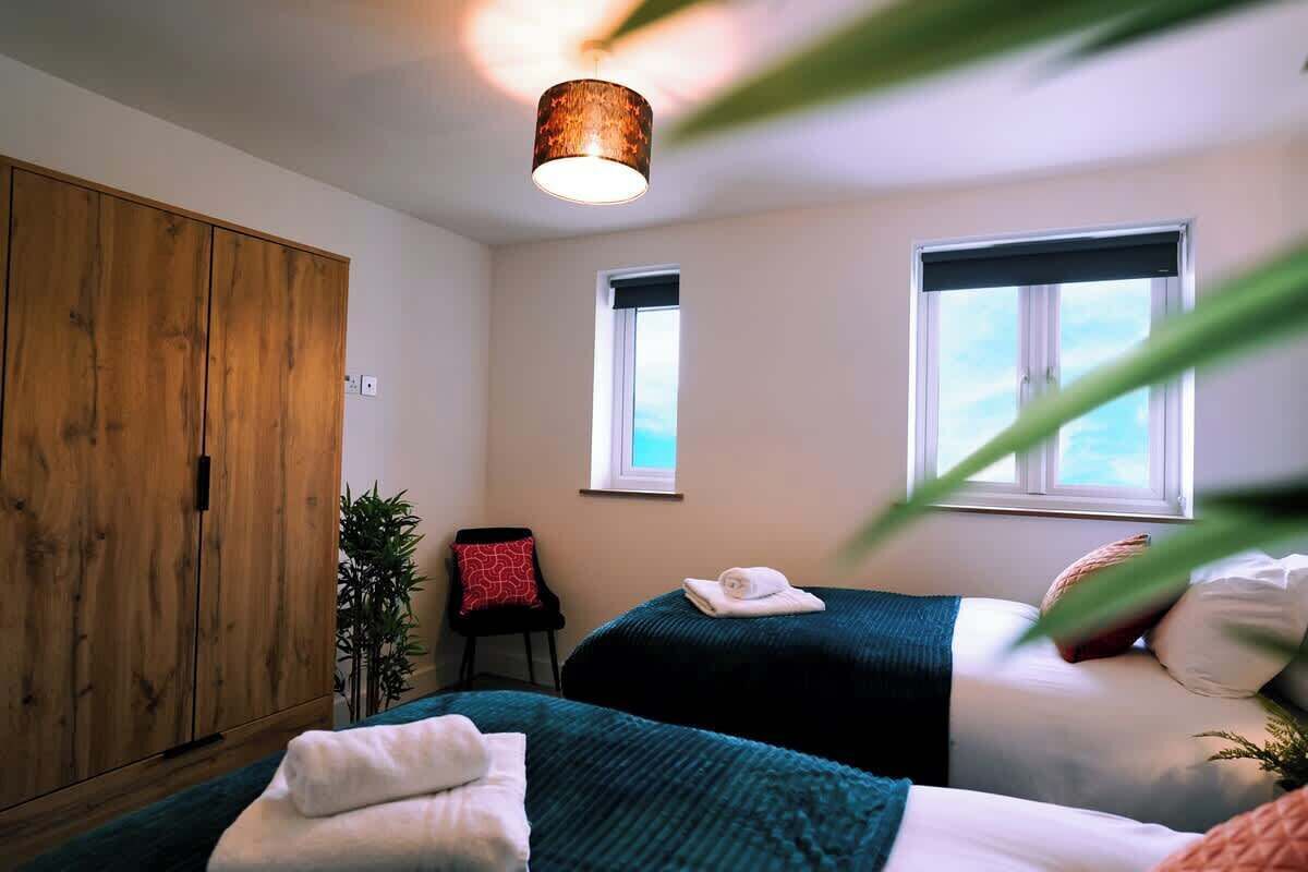 Ein Schlafzimmer mit zwei Betten, einem Holzschrank, einem Fenster und einer Pflanze.