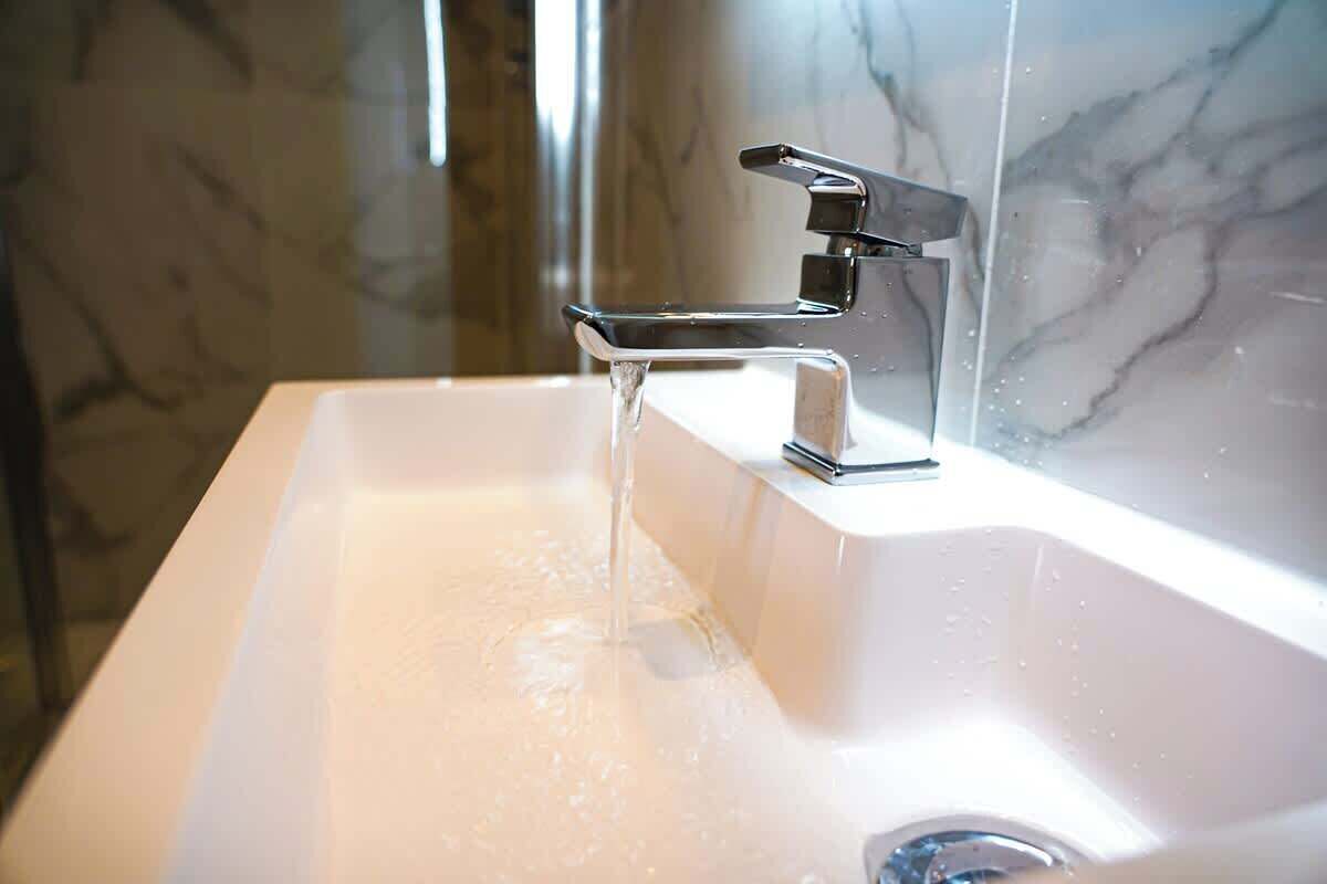 A modern bathroom with a chrome faucet and a marble backsplash.