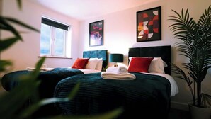 Habitación de hotel con dos camas, una ventana, una planta en maceta y obras de arte en las paredes.