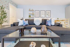 Una sala de estar moderna con un sofá seccional gris, una mesa de centro de vidrio y jarrones decorativos.